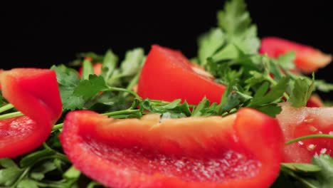 Macro-close-up-of-colorful-fresh-parsley-and-tomatoes-rotating-on-a-black-background