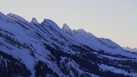 Aerial-view-showcasing-the-silhouette-of-a-snowy-mountain-range-at-dawn