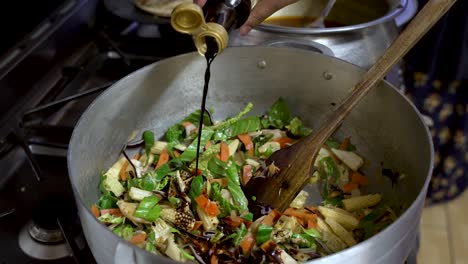 Stir-fry-vegetables-in-wok-with-sauce-pouring,-kitchen-setting,-vibrant-colors