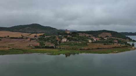 Overcast-day-aerial-view-of-Nanclares-de-Gamboa-village-by-a-calm-lake,-Basque-Country,-Spain,-tranquil-scene