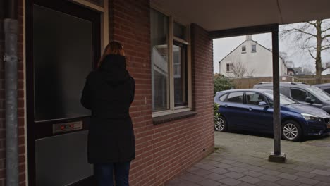 Dolly-out-of-woman-walking-to-her-front-door-and-entering-her-house