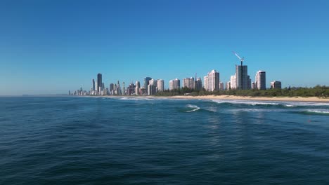 Forward-moving-rising-aerial-view-over-Main-Beach-looking-South-towards-Surfers-Paradise,-Gold-Coast,-Australia