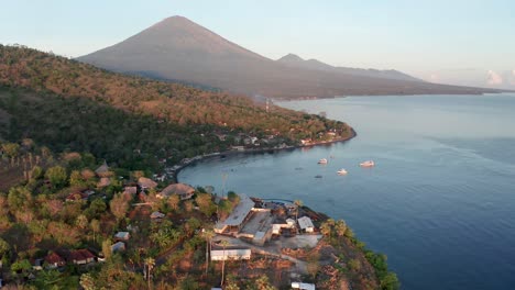 Aerial-view-of-Bali-tourism-town-Amed-with-Mount-Agung-volcano-in-background,-Indonesia