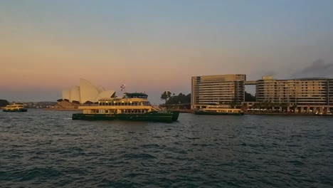 Blick-Auf-Den-Sonnenuntergang-über-Dem-Hafen-Von-Sydney-Mit-Fähren-In-Der-Nähe-Des-Opernhauses,-Warmes-Leuchten-Auf-Dem-Wasser