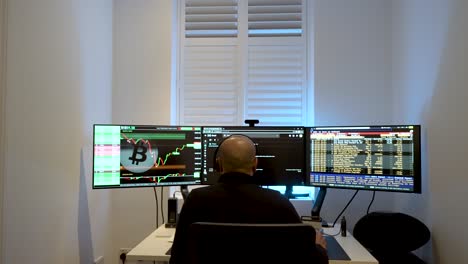 View-From-Behind-Man-analyzing-financial-markets-on-dual-monitors,-blurred-background,-indoor,-dusk-light