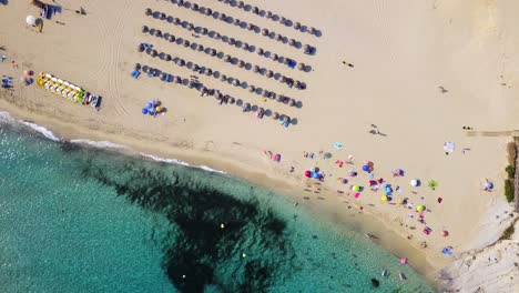 Playa-De-Cala-Mesquida-Con-Coloridas-Sombrillas-Y-Aguas-Cristalinas,-Vista-Aérea,-En-La-Isla-De-Mallorca,-España,-En-El-Mar-Mediterráneo.