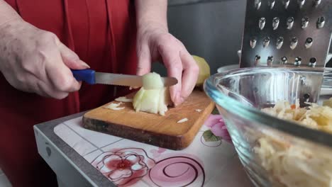 An-elderly-housewife-is-cutting-an-onion-into-cubes-in-the-kitchen