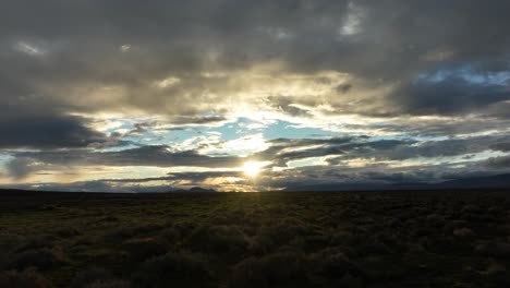 Sunset-over-the-Mojave-with-clouds-casting-shadows-on-the-desert-floor,-hints-of-blue-sky