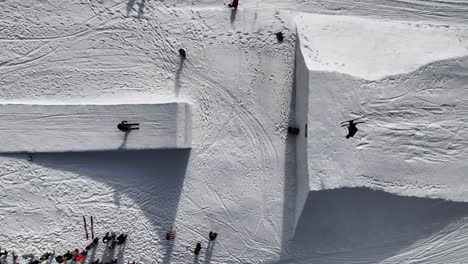 Luftaufnahme-Von-Oben-Nach-Unten-Einer-Schneebedeckten-Rampe,-Skifahrer-Springen-Und-Führen-Tricks-Aus,-Tschechien