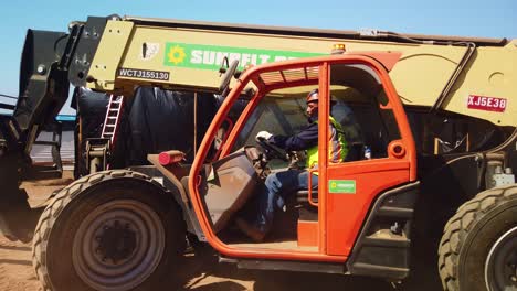 Gimbal-panning-shot-of-an-industrial-fork-lift-operated-by-a-construction-worker-at-a-modular-housing-site-in-West-Los-Angeles,-California