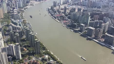 Barcos-Que-Transportan-Mercancías-Y-Materiales-En-El-Río-Huangpu-En-Shanghai,-China,-Vista-Superior-Con-Panorámica-Vertical