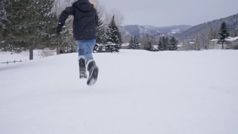 Slow-Motion,-Young-Teenage-Girl-Running-on-Snow-Covered-Field-on-Cold-Winter-Day