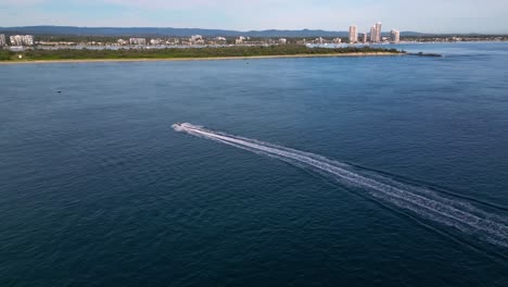 Aerial-views-following-a-jet-ski-near-Wavebreak-Island-over-the-Broadwater-on-the-Gold-Coast,-Australia