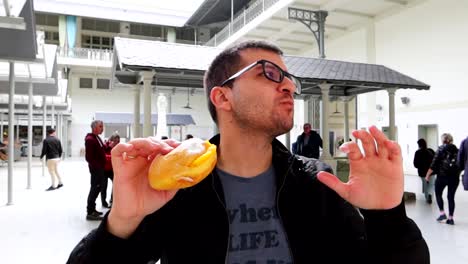 Man-eating-Portuguese-pastry-in-Bolhao-Market-with-excitement,-portrait-view