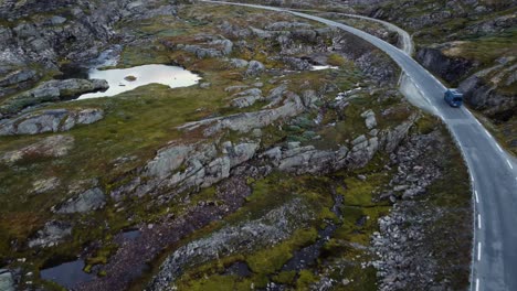 Imágenes-Aéreas-De-Una-Furgoneta-Azul-En-Una-Pequeña-Carretera-En-Noruega