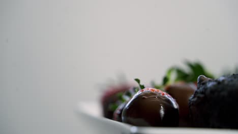 Fresas-Cubiertas-De-Chocolate-Girando-Sobre-Un-Plato-Con-Muffins-De-Chocolate-Y-Remolacha