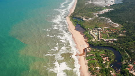 Vista-Aérea-De-Las-Olas,-La-Playa,-Un-Pequeño-Río-Y-La-Zona-De-Palmeras-En-Un-Día-Nublado,-Imbassai,-Bahia,-Brasil