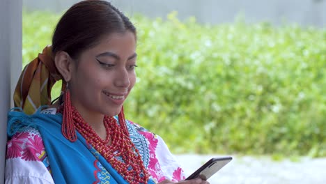 Cinematic-clip-of-a-young-brunette-latin-girl-wearing-the-traditional-outfit-named-Cayambeñas-using-her-phone-and-laughing