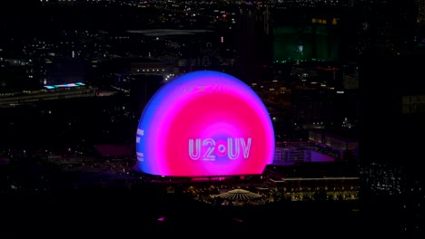 Las-Vegas-city-lights-with-glowing-colorful-Sphere-concert-venue-advertising-the-band-U2