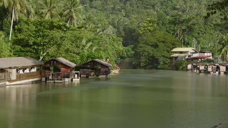 Riverside-huts-nestled-in-lush-greenery-along-the-tranquil-Loboc-River-in-the-Philippines