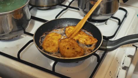 Grandma,-mother-takes-fried-pork-chops-from-the-pan-on-a-gas-stove-at-grandma's