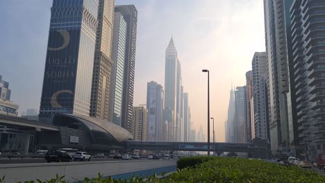 Verkehr-In-Der-Innenstadt-Von-Dubai,-Vereinigte-Arabische-Emirate,-Luftverschmutzung-über-Wolkenkratzern-Und-Der-U-Bahnstation-Emirates-Towers