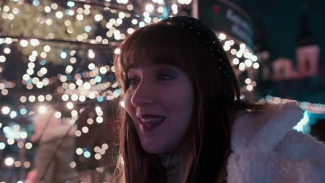 Cerca-Del-Rostro-De-Una-Hermosa-Mujer-Con-Cabello-Oscuro-Que-Muestra-Decepción-En-Un-Mercado-Navideño-Rodeado-De-Luces-Navideñas-Parpadeantes