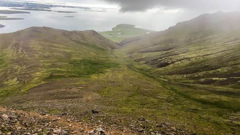 Expansive-Icelandic-valley-with-green-hills-under-cloudy-skies,-conveying-a-serene-landscape