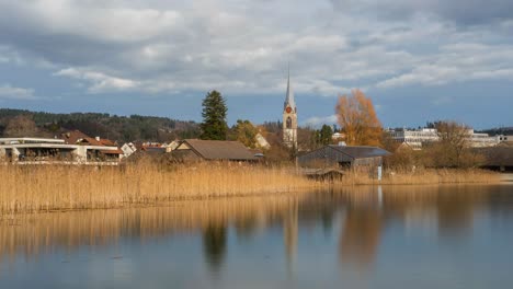 Clouds-move-over-a-church-near-a-lake-in-Switzerland