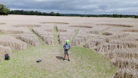 Person-wearing-alien-mask-in-Andover-crop-circle-speed-ramp-aerial-view-to-molecular-pattern-on-golden-wheat-field