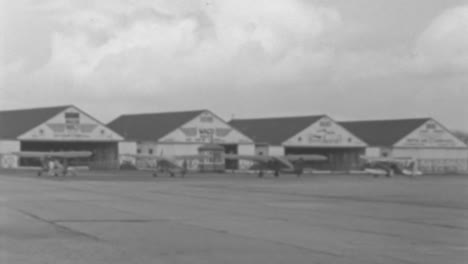 Small-Aircraft-Parked-in-Front-of-Hangars-at-Roosevelt-Field-Airport-in-1930s