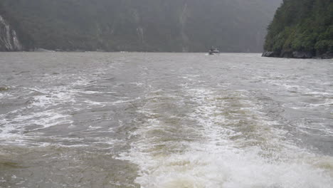 Slow-motion-boat-wake-in-a-fjord-with-another-boat-in-the-background---Milford-Sound-,-New-Zealand