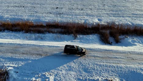 A-black-car-is-driving-down-a-snowy-road