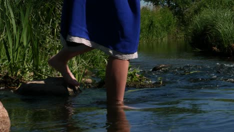 Una-Chica-Vestida-De-Azul-En-La-Orilla-Del-Río-Puso-Lentamente-La-Pierna-En-El-Río