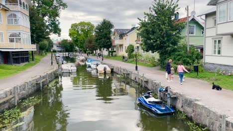 Couple,-child-and-dogs-walk-by-canal-in-small-town-of-Trosa-in-Sweden