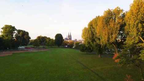 Drohnenflug-über-Einen-Wunderschönen-Park-In-Köln-Bei-Sonnenuntergang-In-Richtung-Des-Berühmten-Kölner-Doms