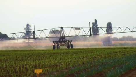 Agricultural-wide-arm-pesticide-sprayer,-automatically-slow-moving-through-a-field-of-multiple-crop-trials-on-a-windy-day,-selective-focus