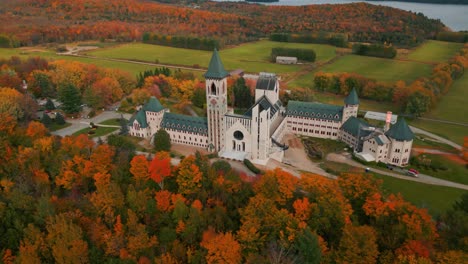 Toma-Aérea-Alrededor-De-La-Abadía-De-Saint-Benoit-Du-Lac-En-Otoño-Con-árboles-Coloridos-Cerca-De-Magog-On-Y-El-Lago-Memphremagog-En-La-Región-De-Quebec,-Temporada-De-Otoño,-Canadá