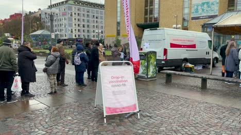 People-in-line-by-drop-in-covid-vaccination-bus-in-Stockholm,-Sweden