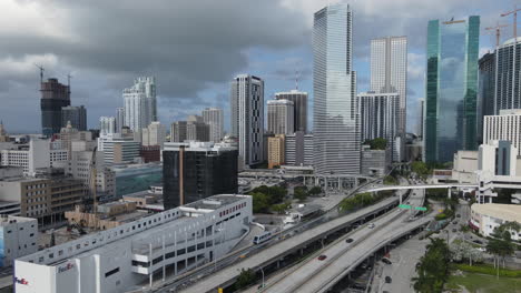 Miami-Florida-USA,-Aerial-View-of-Dade-County-Downtown-Neighborhood,-Skyscrapers-and-Traffic-on-Highway-and-Metromover-Railway,-Drone-Shot