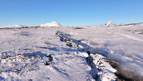 Vapor-Volcánico-Que-Se-Eleva-Desde-El-Paisaje-De-Cráteres-Cubiertos-De-Nieve-En-Islandia,-Avance-Aéreo