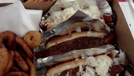 Hot-dogs,-fries-and-onion-rings-from-Pink's-Hot-Dogs-in-Los-Angeles,-California-with-video-tilting-down