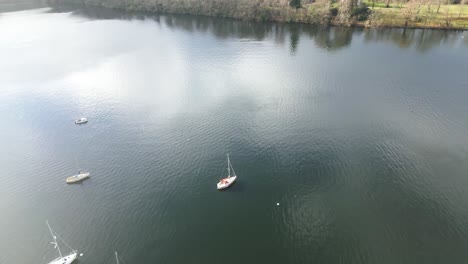 Sailboats-on-dark-watered-lake,-Drone-Flyover