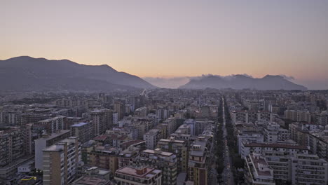 Palermo-Italy-Aerial-v7-tracking-shot-drone-flyover-downtown-area-capturing-sunset-dusk-cityscape,-street-traffics-and-mountainous-landscape-on-the-skyline---Shot-with-Mavic-3-Cine---May-2023