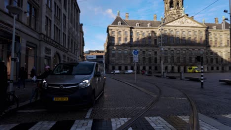 Wide-view-of-busy-streets-and-crosswalk-in-Amsterdam,-Netherlands-with-pedestrians-and-vehicles-driving-during-daytime