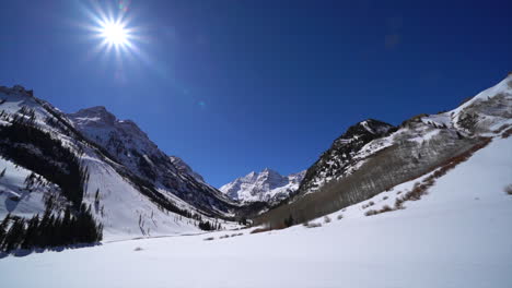 Maroon-Bells-snow-lake-Aspen-Snowmass-spring-winter-avalanche-ranch-snowmobile-trail-Rocky-Mountains-Colorado-Capital-peak-incredible-sunny-blue-sky-panoramic-scenic-landscape-pan-slowly-left-wide