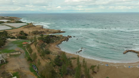 Coastal-view-of-Kapparis,-Paralimni,-showcasing-the-beachfront,-rocky-shores,-and-Mediterranean-Sea-against-an-overcast-sky