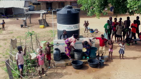 Villagers-in-Pila,-Nigeria-rationing-water-supplied-by-borehole-and-tank-system