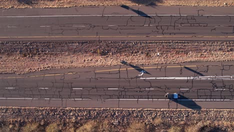 Birdseye-Aerial-View-of-Old-American-Freeway,-Cars-Moving-on-Cracked-Asphalt,-High-Angle-Drone-Shot