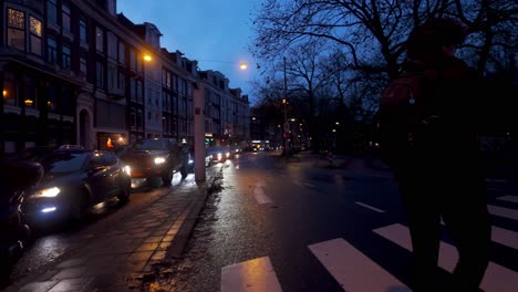 Nächtlicher-Blick-Auf-Den-Dichten-Autoverkehr-Und-Die-Fußgänger,-Die-Die-Straßen-Von-Amsterdam,-Niederlande,-überqueren